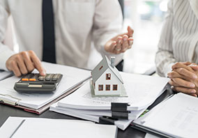 Lawyers discussing estate tax planning with model house and financial documents on table